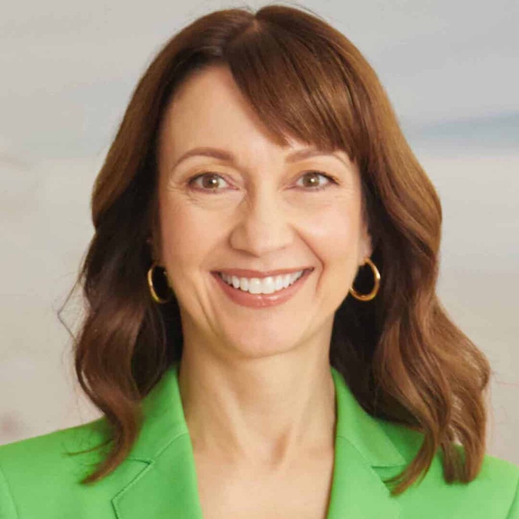 Professional headshot of Dr. Marie-Hélène Pelletier wearing a bright green top, posing in front of a grey studio background.