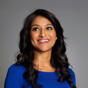 Rinki Sethi. Headshot of Rinki Sethi wearing a bright blue top. She is smiling and posing in front of a plain grey background.