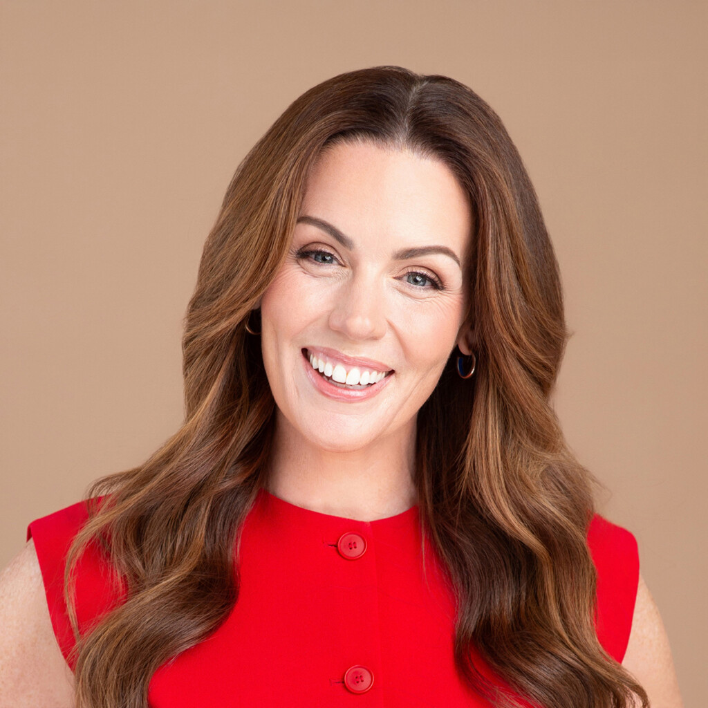 Dr. Robyne Hanley-Dafoe. Headshot of Dr. Robyne Hanley-Dafoe, smiling, wearing a red short-sleeve top and posing in front of a light brown background.