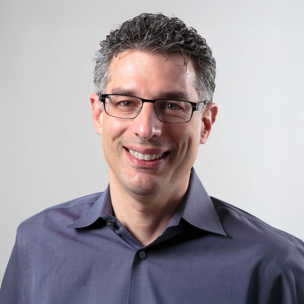 Robert Safian. Headshot of Robert Safian wearing a blue collared shirt, posing in front of a white background.