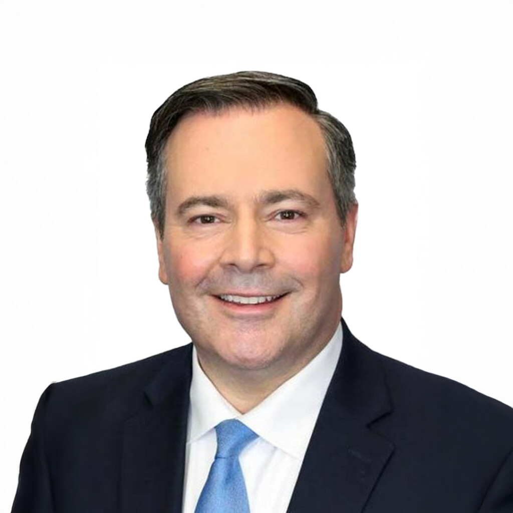 Jason Kenney. Headshot of Jason Kenney wearing a black suit and a white shirt with a light blue tie. He is posing in front of a bright white background.