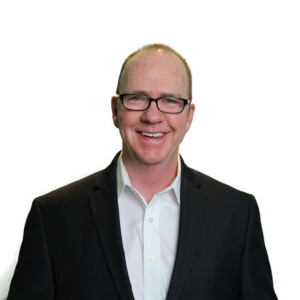 Eddit LeMoine. Headshot of Eddit LeMoine wearing a black suit over a light blue shirt. He is posing in front of a bright white background.