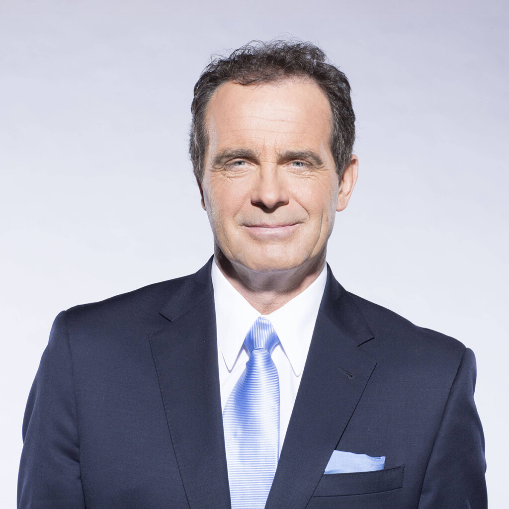 Rod Black. Headshot of Rod Black wearing a dark blue suit with a light blue tie. He is posing in front of a bright gradient background.