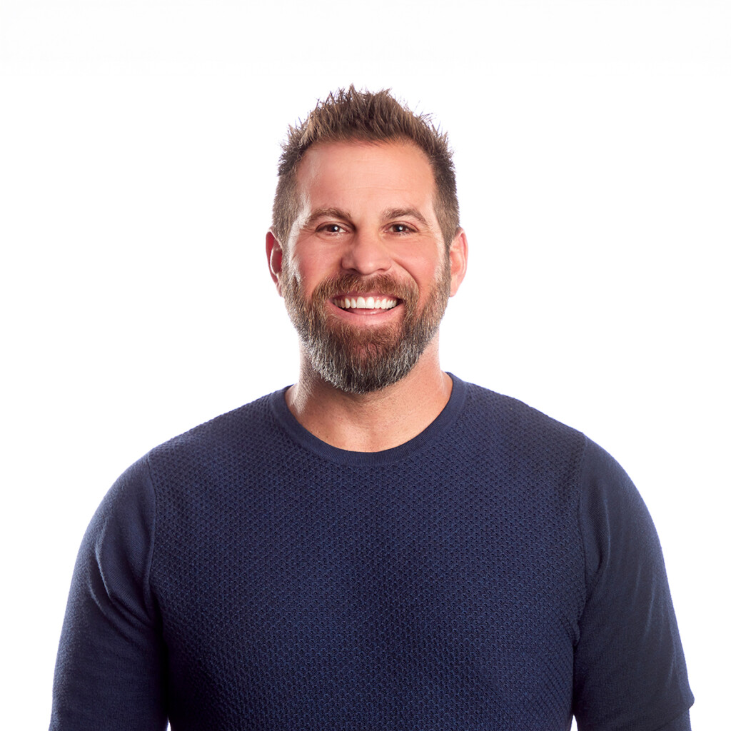 Jon Dorenbos. Headshot of Jon Dorenbos wearing a navy sweater and standing in front of a bright white backdrop.