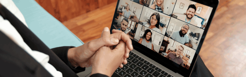 A laptop sitting on someone's lap. The person seems to be in a video call with other users. Everyone's faces are shown on the video call screen.