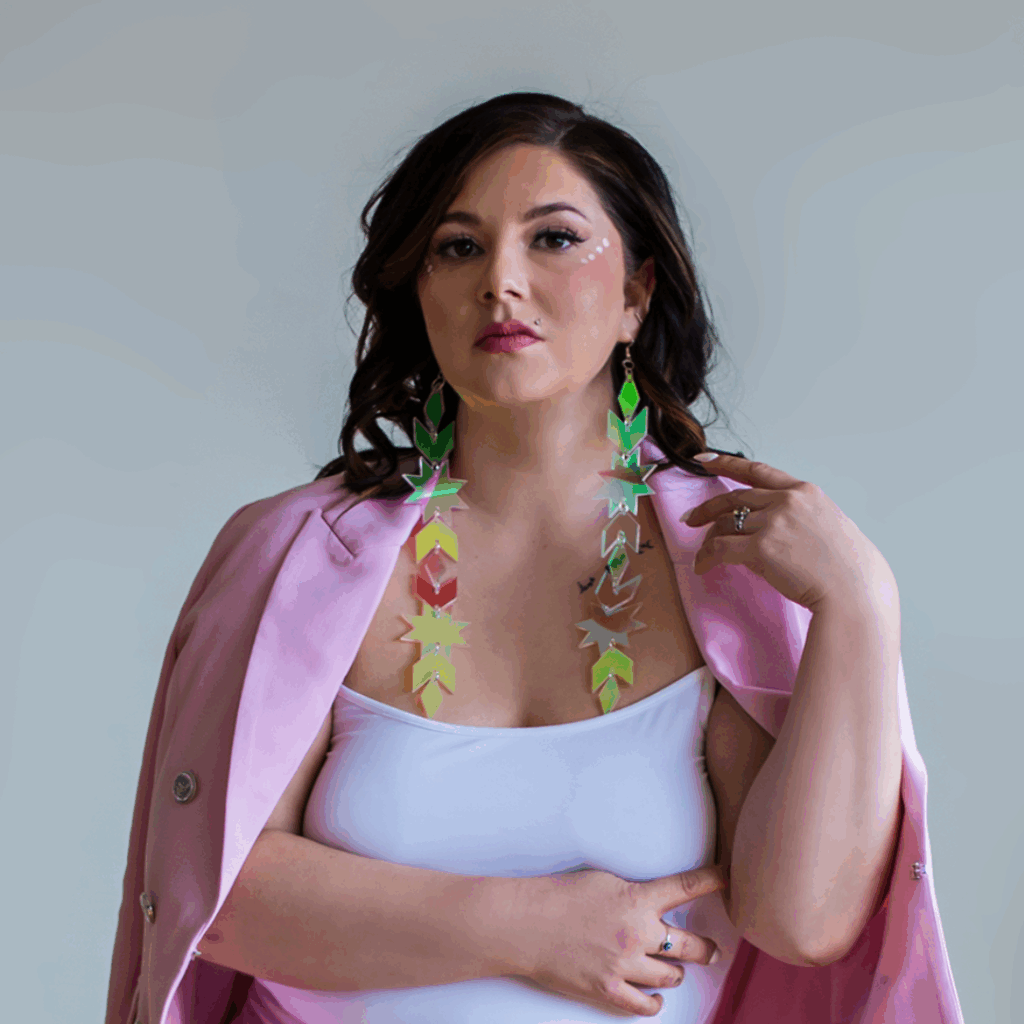 Headshot of Dr. Candace Linklater, speaker and founder, wearing a white top, bright pink blazer and long, colourful holographic earrings.