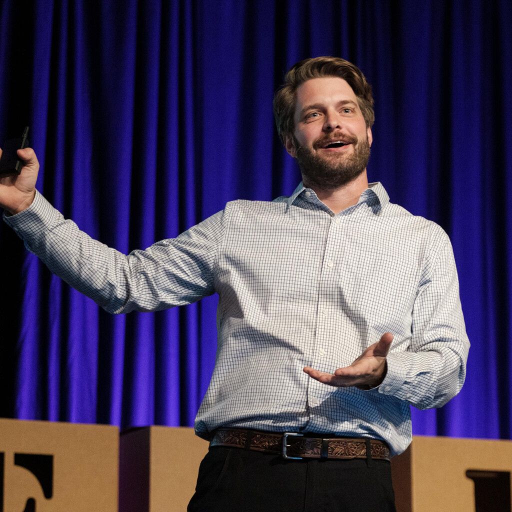 Kyle Scheele. Headshot of Kyle Scheele in action during a speaking event on stage.