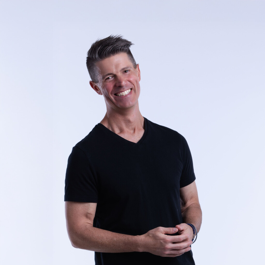 Rich Bracken. Headshot of Rich Bracken wearing a black t-shirt, standing in front of a white background.