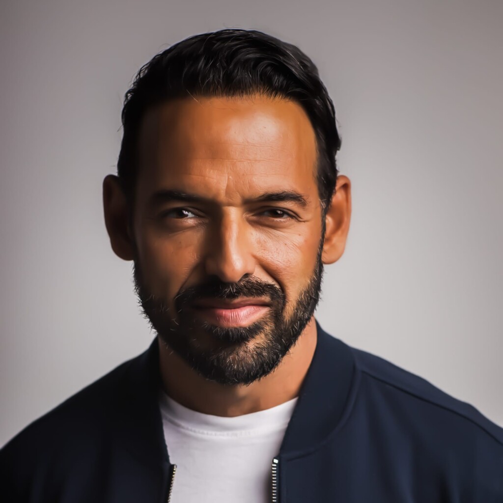 Close-up headshot of Shaun Majumder in front of a grey background.