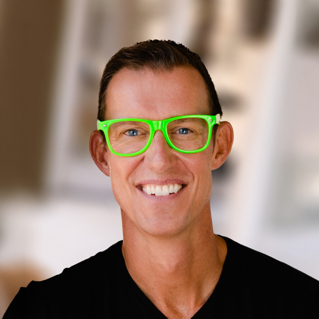 Erik Qualman. Headshot of Erik Qualman wearing a black shirt and neon green glasses.