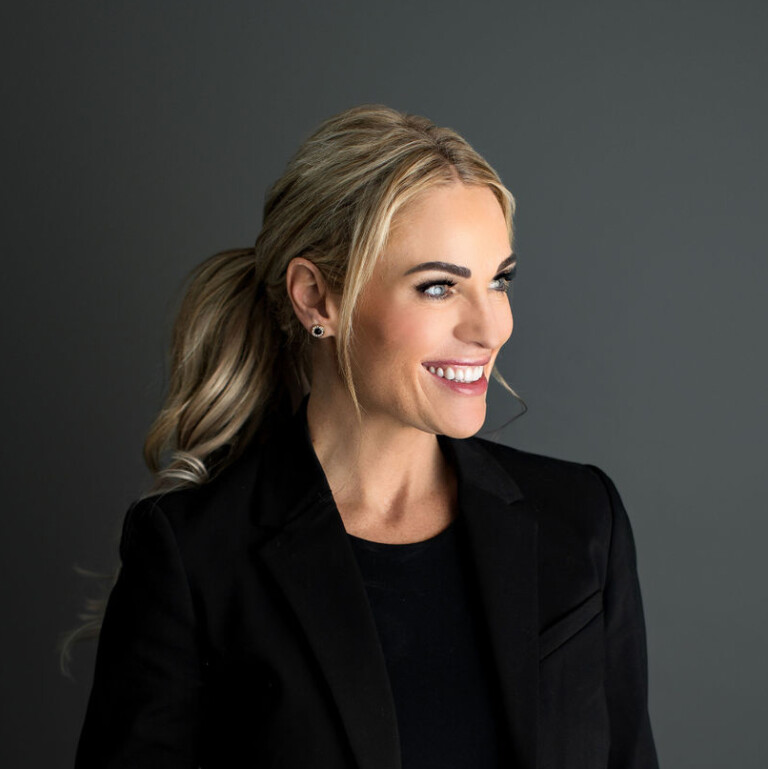 Rebecca Bultsma. Professional headshot of Rebecca Bultsma wearing a black jacket over a black top. Studio lighting with a grey backdrop.
