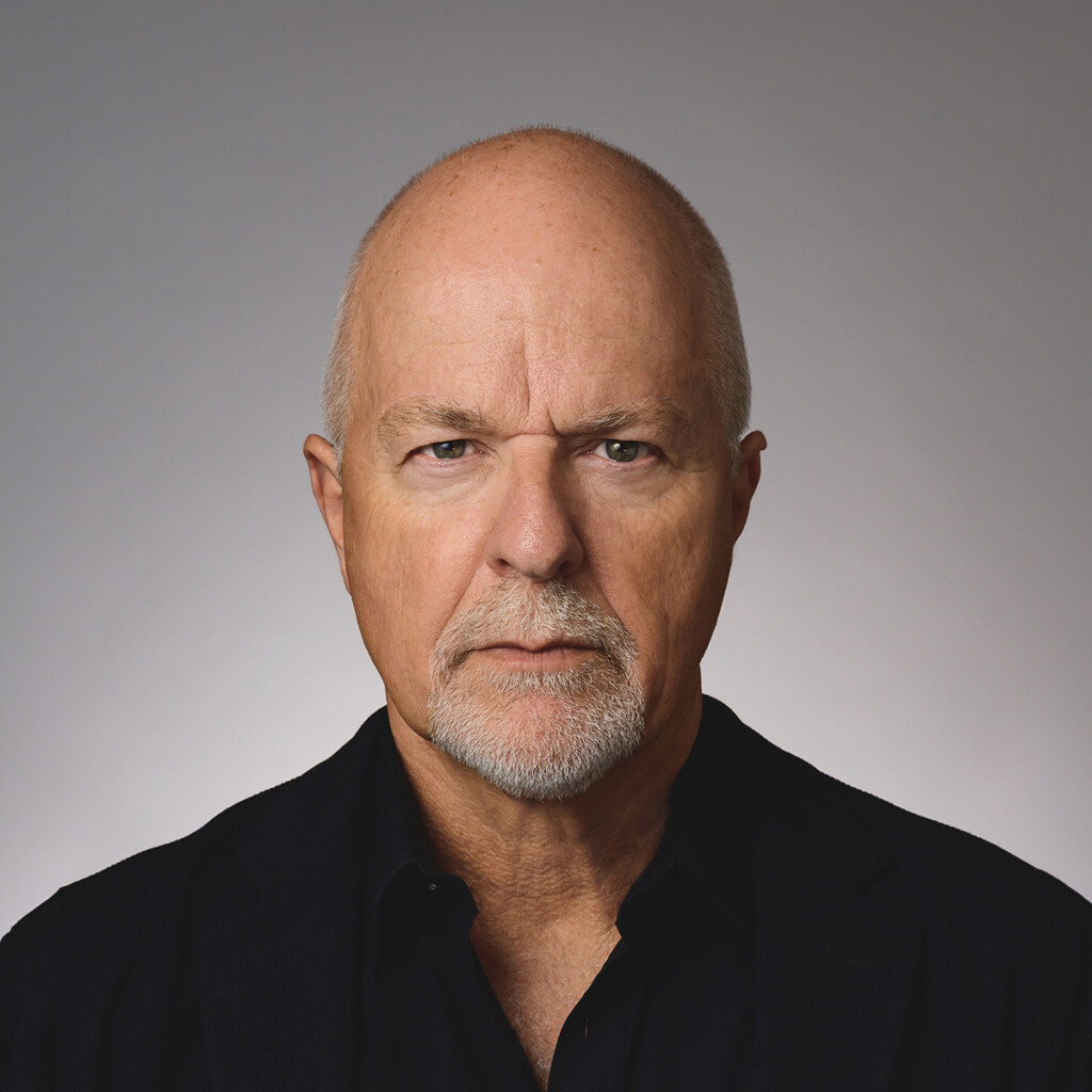 Professional headshot of Chris Mathers wearing a black shirt, posing in front of a grey studio back drop.
