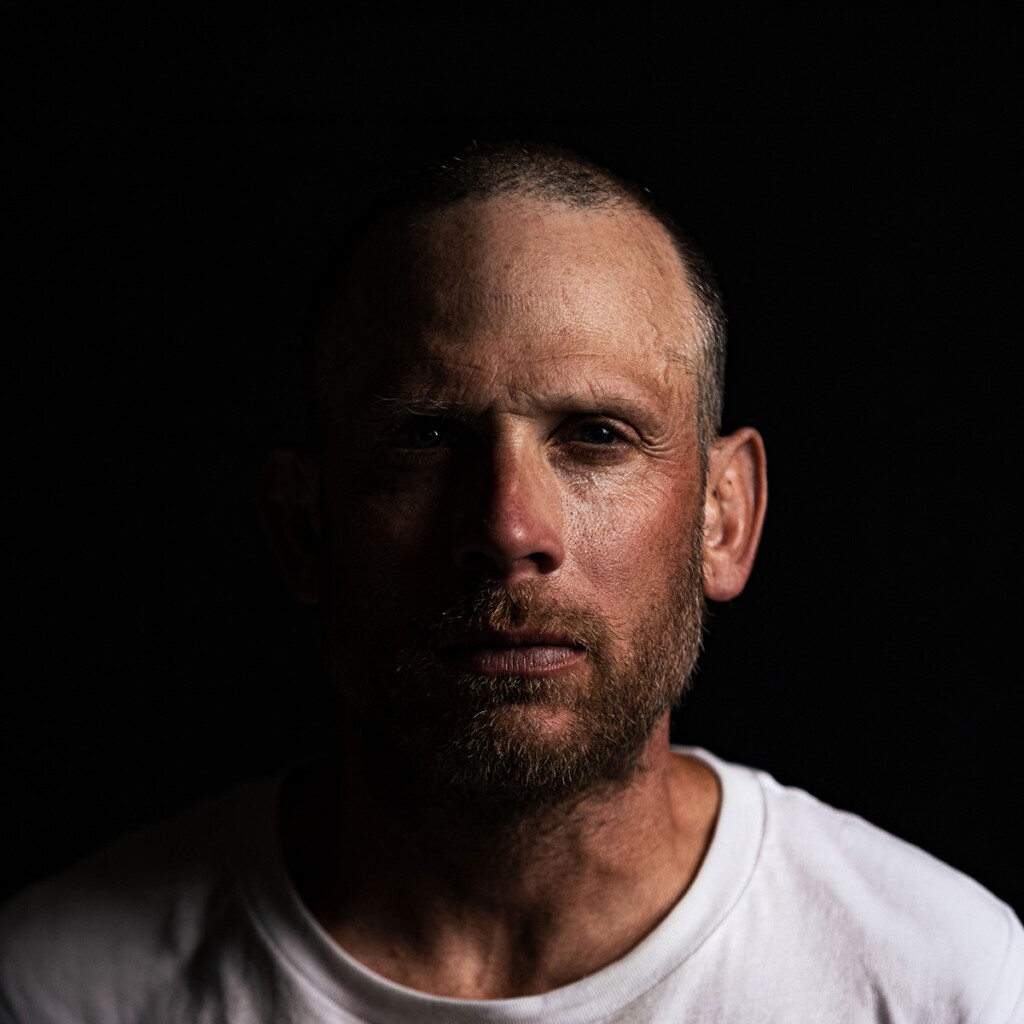 Professional headshot or James Lawrence wearing a white shirt posing in front of a dark studio back drop.